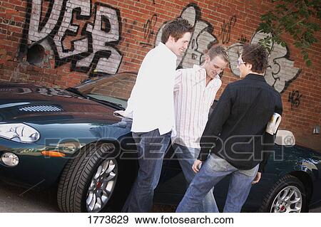 Stock Photo - Group of guys hanging around car. Fotosearch