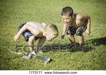 Stock Image - Little boys playing with a sprinkler. Fotosearch