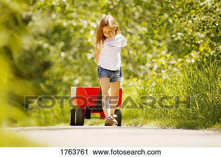 A little girl pulling a red wagon View Large Photo Image Stock Image - A little girl pulling a red wagon. Fotosearch