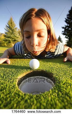 Stock Image - Girl blows ball into hole. Fotosearch