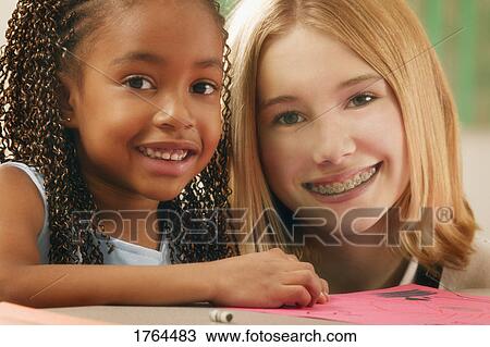 Stock Image - Two girls color together. Fotosearch