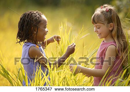 Two girls in tall grass View Large Photo Image Stock Photo - Two girls in tall grass. Fotosearch