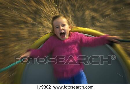 Stock Image - Young girl on playground ride. Fotosearch