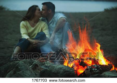 Couple keep warm by campfire View Large Photo Image Stock Image - Couple keep warm by campfire. Fotosearch