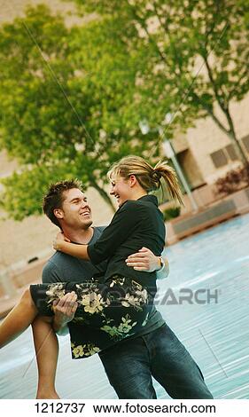 Stock Photo - Man carrying woman over water. Fotosearch