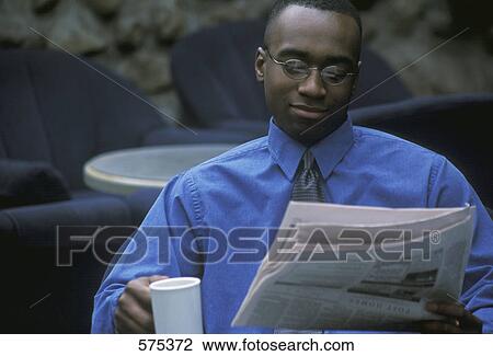 Stock Image - Businessman having coffee and reading the newspaper. Fotosearch