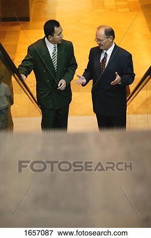 Two men have a discussion on an escalator View Large Photo Image Stock Photo - Two men have a discussion on an escalator. Fotosearch