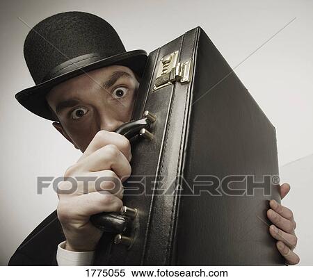 Stock Photography - Man peering over his briefcase. Fotosearch