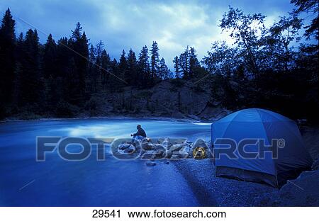 Stock Image - Camper and tent by river. Fotosearch