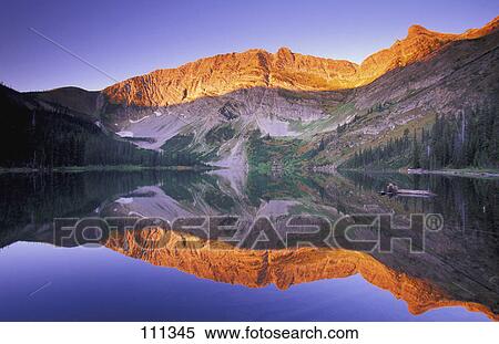 Stock Photography - Mountain at sunset viewed across calm lake. Fotosearch