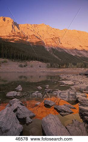 Shore of calm lake with mountain behind on a clear day View Large Photo Image Stock Photo - Shore of calm lake with mountain behind on a clear day. Fotosearch
