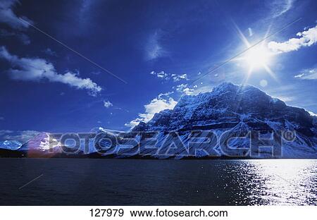 Snow-covered mountains across lake View Large Photo Image Stock Photo - Snow-covered mountains across lake. Fotosearch