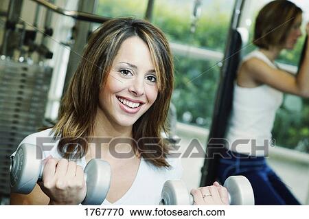 Stock Image - A woman lifts weights. Fotosearch