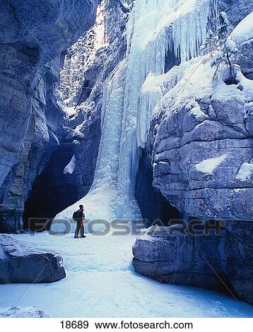 Hiker at base of ice cliff View Large Photo Image Stock Photo - Hiker at base of ice cliff. Fotosearch