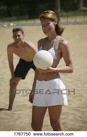 Stock Image - Woman holds volleyball. Fotosearch