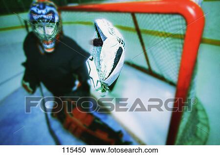 Stock Image - Young goalie in net with glove extended. Fotosearch