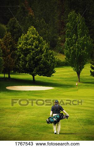 Stock Image - A golfer walking on course. Fotosearch