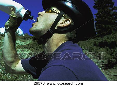 Cyclist drinking from water bottle View Large Photo Image Stock Image - Cyclist drinking from water bottle. Fotosearch