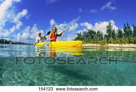 Stock Image - Man and woman in yellow kayak in shallow water. Fotosearch