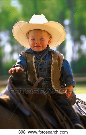 Stock Photo - Toddler in western clothes sitting on a horse. Fotosearch