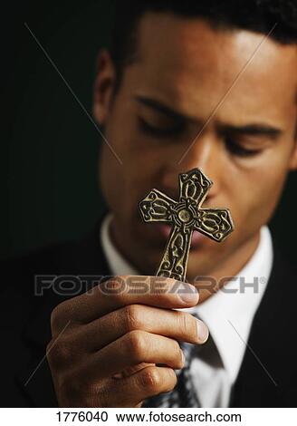 Stock Image - Businessman holding out a cross. Fotosearch