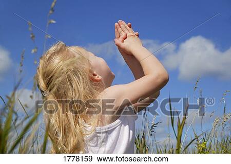 Stock Photo - Child lifts her hands to the sky. Fotosearch