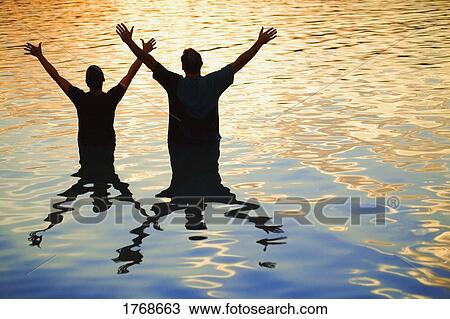 Stock Image - In the water with hands raised. Fotosearch