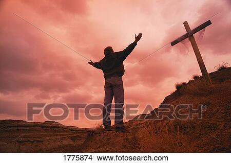 Picture - Man at cross with raised arms. Fotosearch