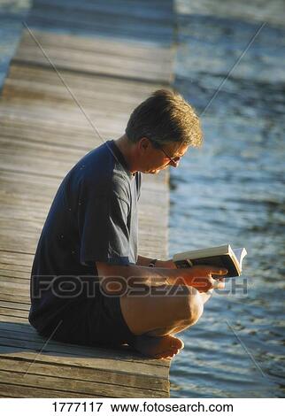 Man reading his book by the waterside View Large Photo Image Stock Photo - Man reading his book by the waterside. Fotosearch
