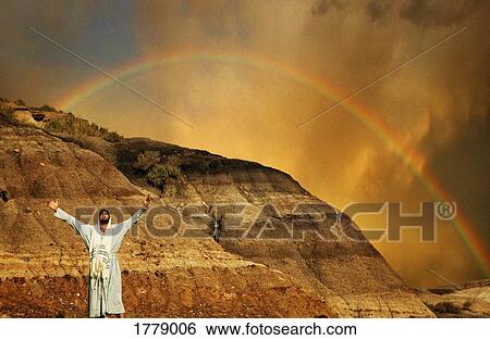 Stock Photograph - Man with outstretched arms, rainbow in background. Fotosearch