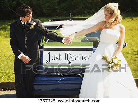 Stock Photography - Couple hold hands by wedding car. Fotosearch