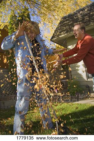 Stock Photography - Father throws leaves at son. Fotosearch