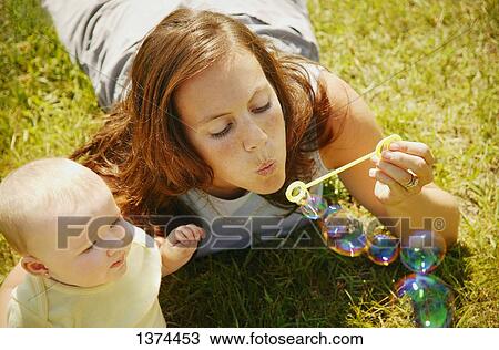 Mom blows bubbles for baby View Large Photo Image Stock Image - Mom blows bubbles for baby. Fotosearch