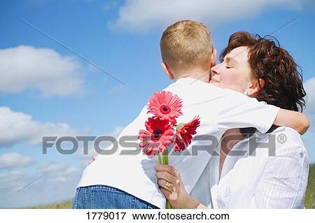 Stock Photo - Son gives mother flowers. Fotosearch