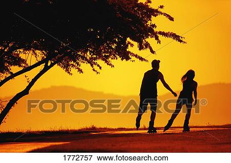 Stock Photo - A couple of rollerbladers at sunset. Fotosearch