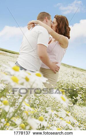 Stock Photo - Couple kissing in a field of daisies. Fotosearch