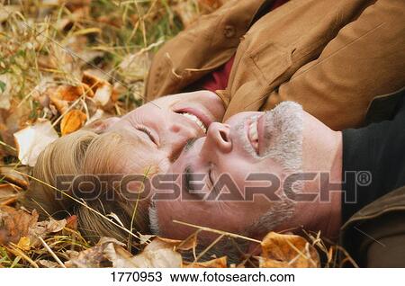 Stock Image - Couple lying in leaves. Fotosearch