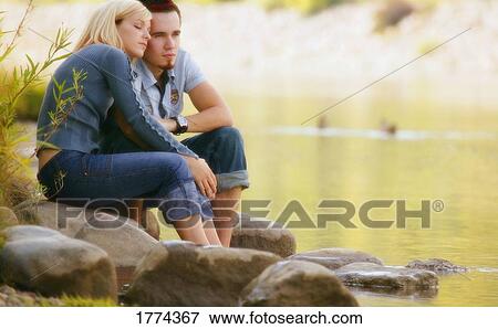 Couple sitting near water View Large Photo Image Stock Photo - Couple sitting near water. Fotosearch