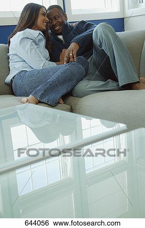 Stock Photograph - Couple snuggles on sofa. Fotosearch