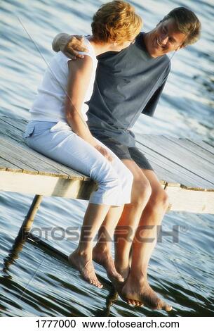 Stock Image - Couple talking on dock. Fotosearch