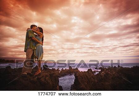 Stock Photo - Romantic embrace against sky and ocean. Fotosearch