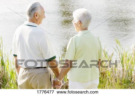 Picture - Senior couple by the river. Fotosearch - Search Stock Photography, Photos, Prints, Images, and Photo Clipart