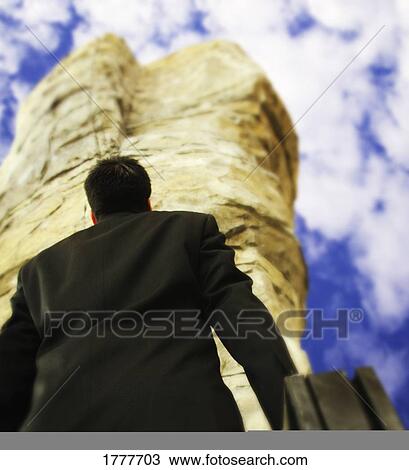 Stock Image - A businessman gazing at a pillar of stone. Fotosearch