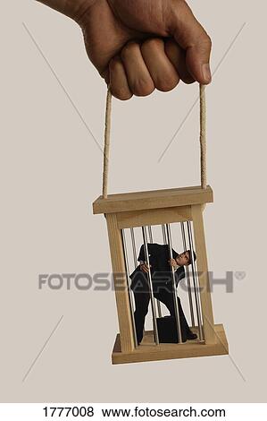 A hand holding a business man in a cage View Large Photo Image Stock Photo - A hand holding a business man in a cage. Fotosearch