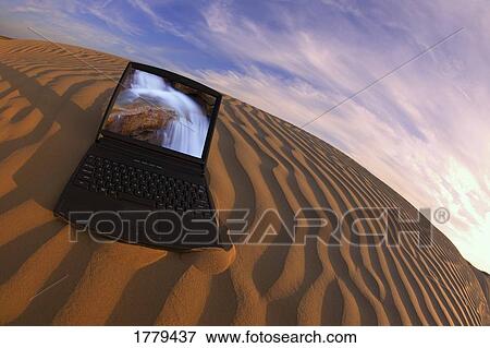 Stock Photo - A laptop displaying water in the dessert. Fotosearch