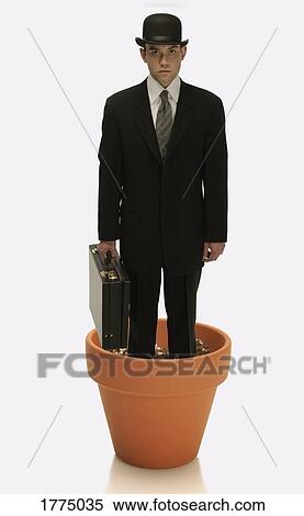 Man in suit with bowler hat and briefcase standing in a flower pot View Large Photo Image Stock Photography - Man in suit with bowler hat and briefcase standing in a flower pot. Fotosearch