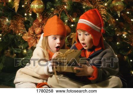 Stock Photo - Children looking inside Christmas present. Fotosearch