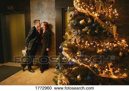 Close professional couple by a Christmas tree View Large Photo Image Stock Image - Close professional couple by a Christmas tree. Fotosearch