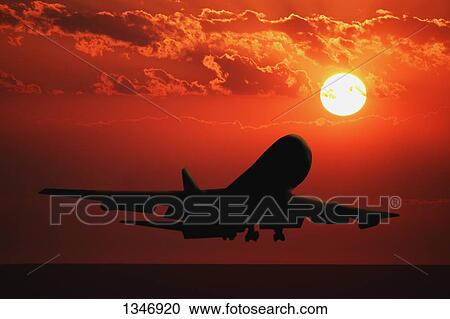 Stock Image - Airplane landing at sunrise/sunset. Fotosearch