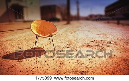 Stock Photo - Empty woven chair on empty street. Fotosearch